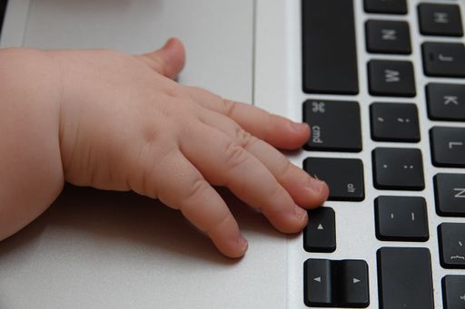 A closeup shot of a baby's hand on a computer keyboard