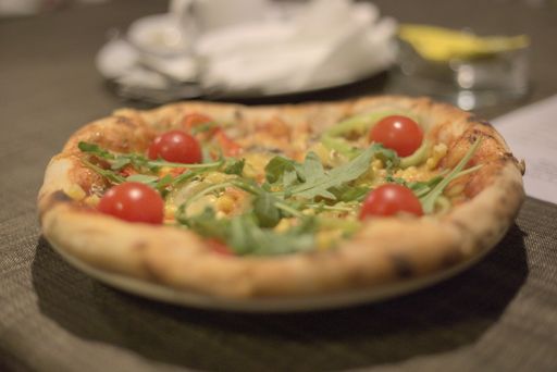A closeup shot of a pizza with cherry tomatoes on a dark brown table
