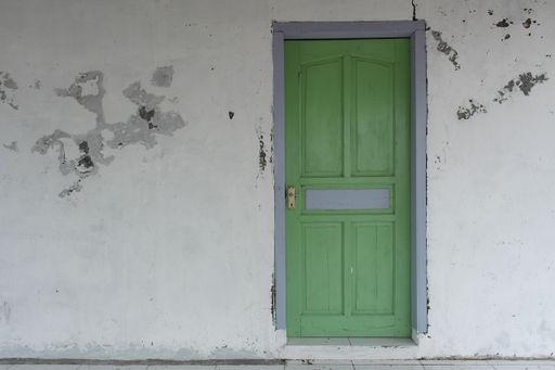A beautiful shot of a green door on a white wall in Indramayu