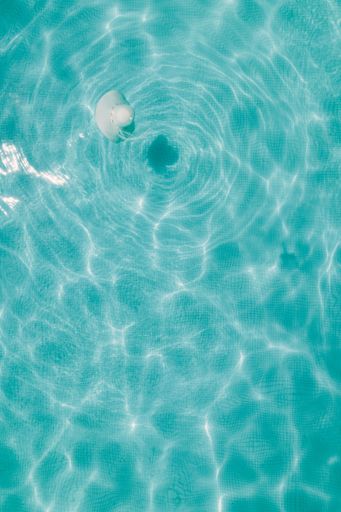 A vertical closeup shot of the light blue transparent water of a pool