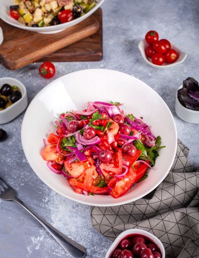 A vertical shot of a tomato salad with onions in a bowl