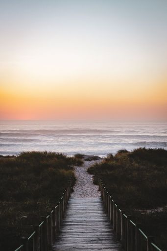 A vertical shot of a wooden bridge leading up to the Bolonia beach at sunset