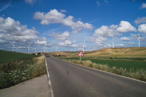 A beautiful view of a highway in the middle of windmill lands in the countryside