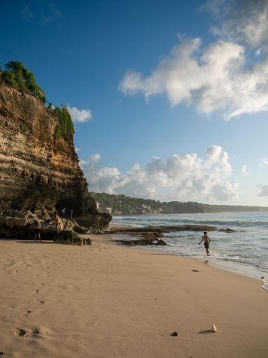 A beautiful view of people on a sandy beach with cliff on a sunny day