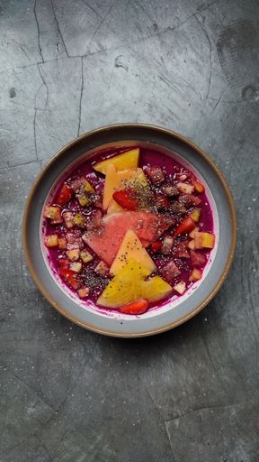 A vertical top view of a delicious acai yogurt fruit bowl