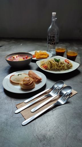 A vertical shot of a delicious arranged dinner with two glasses of drinks and cutlery on a table