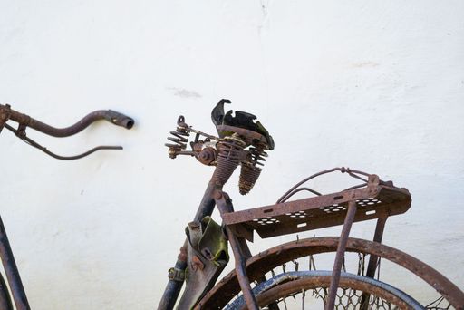 Old rusty bicycle leaning against a white wall, closeup shot