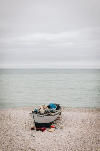 A vertical shot of empty beach on sandy shore under cloudy sky