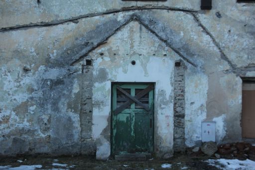 A closeup shot of an old abandoned building with green wooden locked door