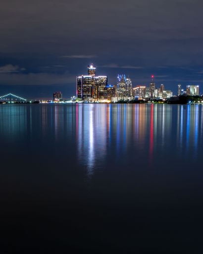 A vertical shot of the lit up city at night from the Belle Isle in Detroit, Michigan