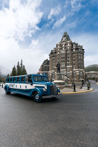 A vertical shot of a retro car parked in front of the Banff Springs hotel in Canada