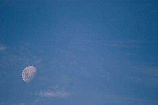 The white moon slightly seen in the blue sky