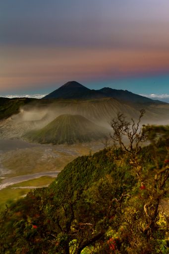 A vertical shot of beautiful green mountains and Bromo volcano in Indonesia under the colorful sky