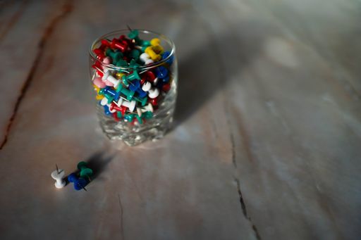A closeup shot of colored small office buttons on glass with wooden background