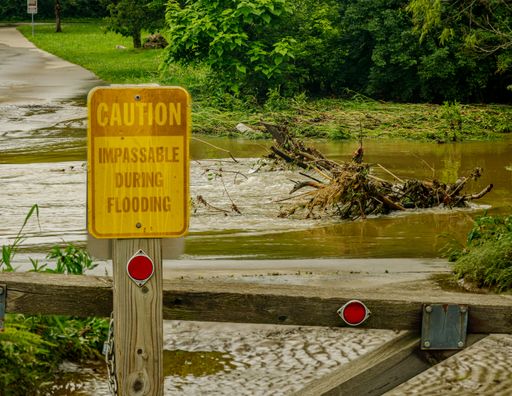 A sign with a caution IMPOSSIBLE DURING FLOODING in the park in flooded path after a heavy rain in Gladstone