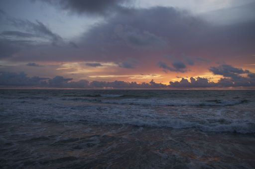 A beautiful shot of sea waves hitting the shore under a dark cloudy sky