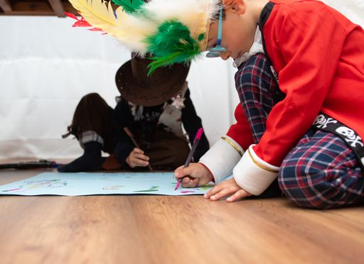 A closeup shot of two kids drawing together sitting on the floor