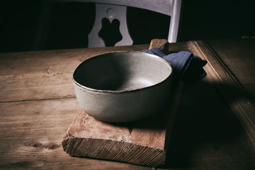 A closeup shot of old empty metal bowl on cutting board on wooden table.
