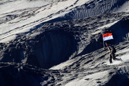 A beautiful view of a person with the Flag of Indonesia on a mountain in East Java
