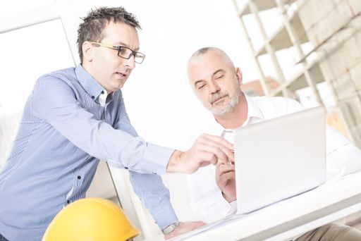 A dutch angle shot of a senior architect teaching his assistant