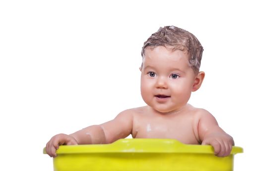 An adorable baby in the green bathtub on an isolated background