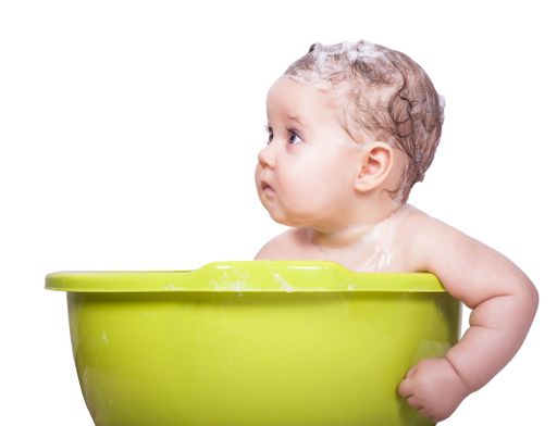 An adorable baby in the green bathtub on an isolated background