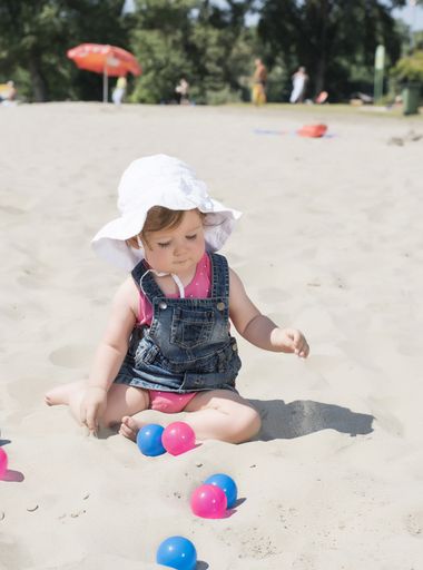A vertical shot of a caucasian baby playing at the beach