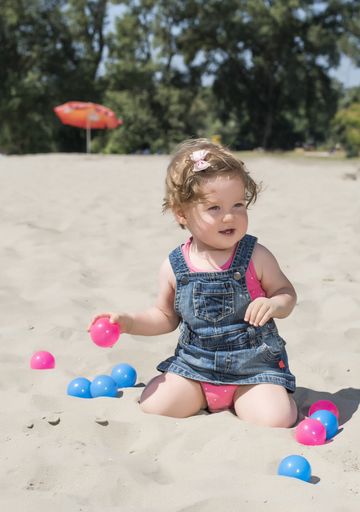 A vertical shot of a cute little girl playing in sands