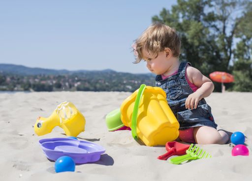 A vertical shot of a caucasian baby playing at the beach