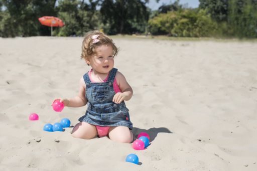 A shallow focus shot of a cute baby playing on a sandy beach