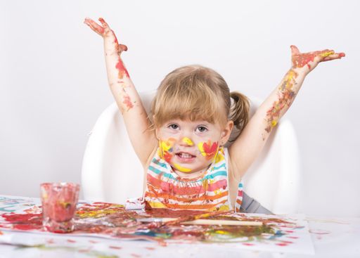 A selective focus shot of a little girl painting and playing