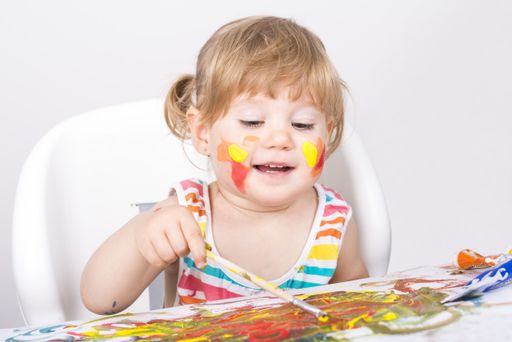 A selective focus shot of a little girl painting and playing
