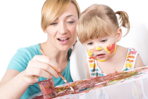 A selective focus shot of a little girl painting and playing with her mom