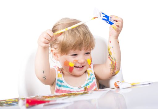 A selective focus shot of a little girl painting and playing