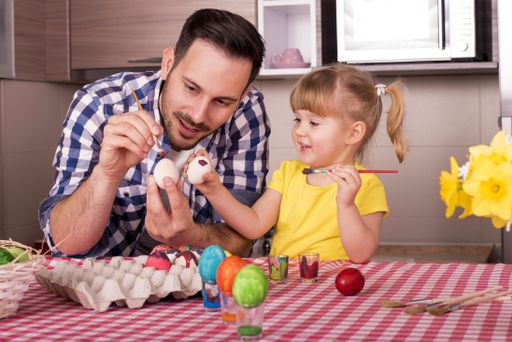 The father and his little child  painting the easter eggs