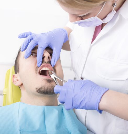 A selective focus shot of a female dentist treating a male patient