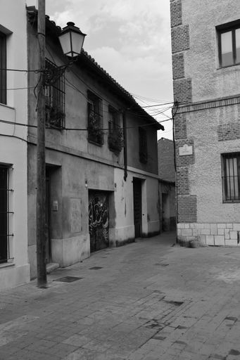 A vertical black and white shot of an old town alley in Alcala de Henares, Spain