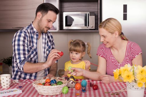 The beautiful family painting the easter eggs with their little child