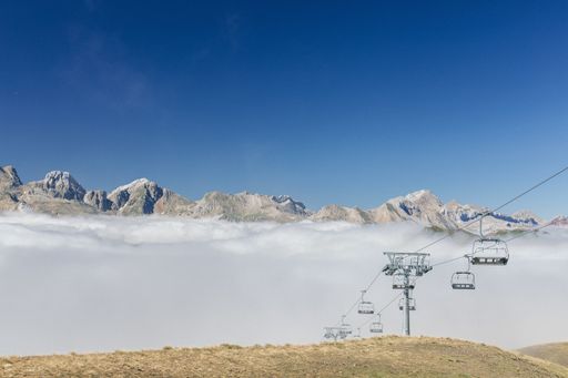 A low angle shot of a beautiful view of the mountains with a chairlift line going through the clouds