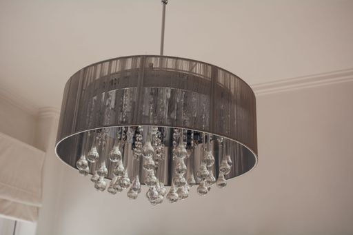 A low angle shot of a decorative crystal chandelier hanging from a white ceiling