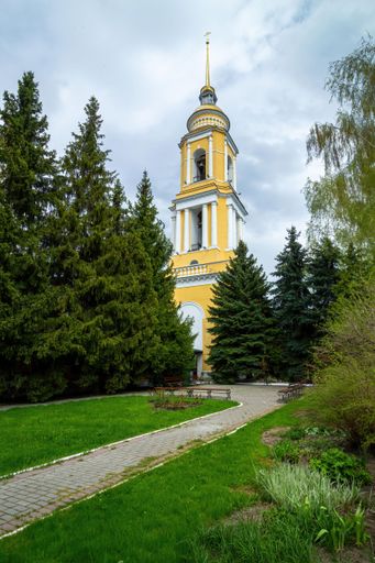 A low angle shot of the bell tower through the pine trees . Novo-Golutvinsky Monastery on Cathedral Square, Kolomna, Russia
