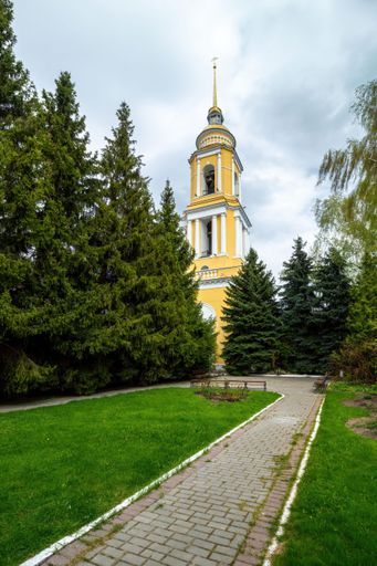 A low angle shot of the bell tower through the pine trees . Novo-Golutvinsky Monastery on Cathedral Square, Kolomna, Russia