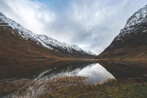 A beautiful shot of a lake in the middle of snowcapped mountains in Glencoe, Highland, Scotland