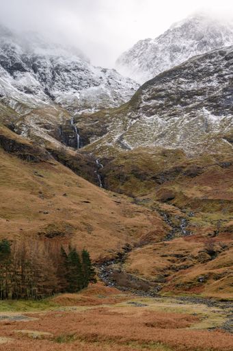 A vertical shot of snowcapped mountains in the Glencoe village in Glen Coe, Scottish Highlands