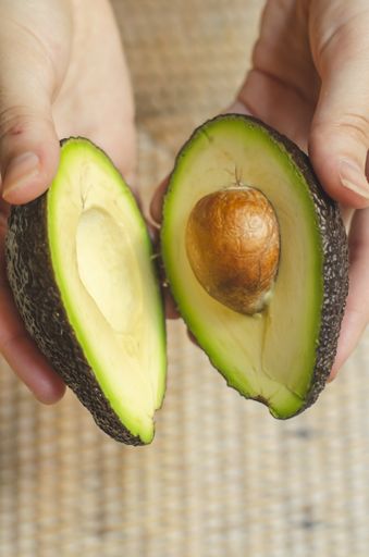 A closeup shot of a person holding sliced avocado