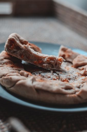 A vertical shot of an apple pie with cinnamon on a blue plate