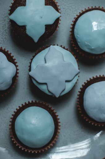 A vertical shot of chocolate cupcakes with blue toppings