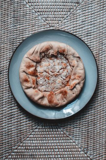 A vertical shot of an apple pie with cinnamon on a blue plate