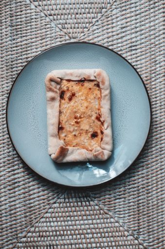 A high angle shot of an apple pie with cinnamon on a blue plate