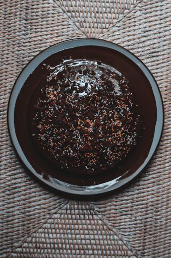 A top view of moist chocolate cake with sprinkle toppings on a blue plate
